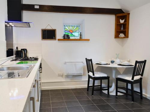 a kitchen with a table and chairs and a sink at Oak Apple Cottage in Upottery