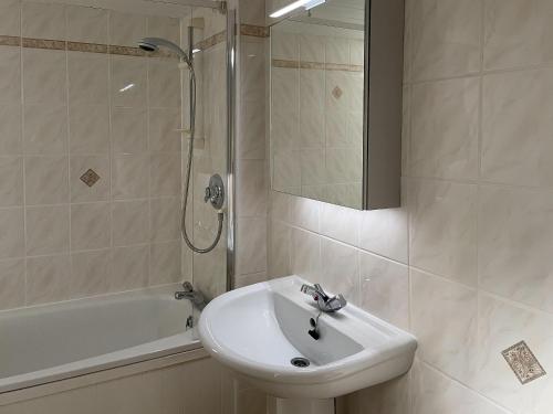 ein weißes Bad mit einem Waschbecken und einer Dusche in der Unterkunft Bunbury Cottage in Keswick