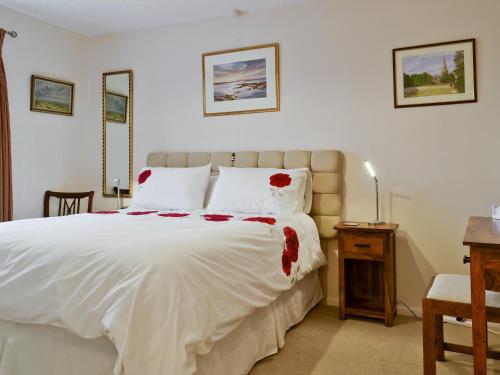 Un dormitorio con una gran cama blanca con flores rojas. en Trentham Cottage, en Snettisham
