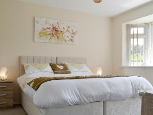 a white bedroom with a large bed with flowers on the wall at Jasper in Broadstone