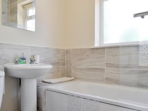 un bagno bianco con lavandino e vasca di Jasper a Broadstone