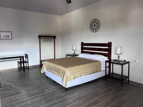 a bedroom with a bed and two tables and a piano at Wally’s Place in Estelí