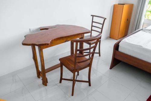 a wooden table and chairs in a room with a bed at G A Villa Airport Transit Hotel in Katunayake