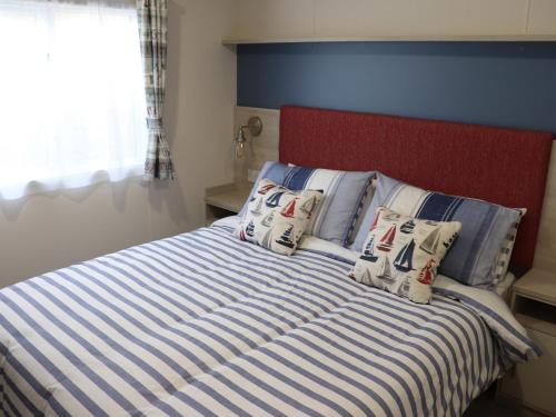 a bed with blue and white striped sheets and pillows at The Retreat in Budleigh Salterton