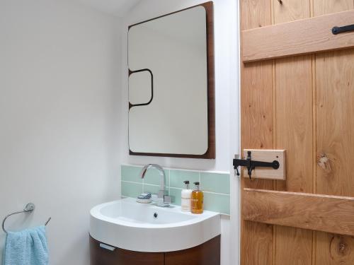 a bathroom with a white sink and a mirror at Bramble Cottage Mountain Retreat in Twyn Llanan