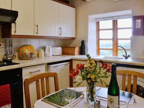 a kitchen with a table with a bottle of wine and flowers at River Wye View Cottage in Symonds Yat