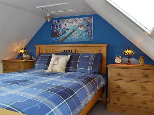 a blue bedroom with a bed with a cat sitting on it at Gracedieu in Killin