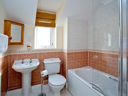 a bathroom with a toilet and a sink and a tub at 52 Moorings Reach in Brixham