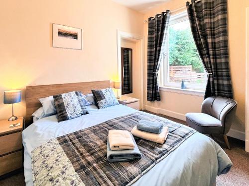 a bedroom with a bed with a chair and a window at Ardgay in Fort Augustus