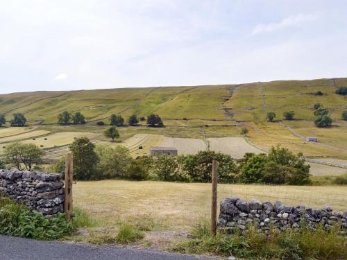 ein Feld mit einem Zaun und einer Steinmauer in der Unterkunft Harrys Hideaway in Laverton