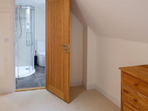 La salle de bains est pourvue d'une douche et d'une porte en bois. dans l'établissement The Fish House, à Rispond