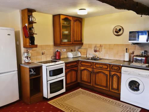 a kitchen with wooden cabinets and a white appliance at Moorland Retreat in Barbrook