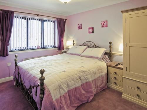 a bedroom with a large bed and a dresser at Llamedos - Hw7771 in Llandudno