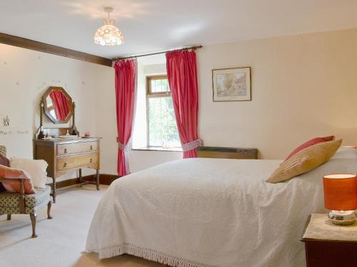 a bedroom with a bed and a dresser and a window at Forget Me Not Cottage in New Radnor