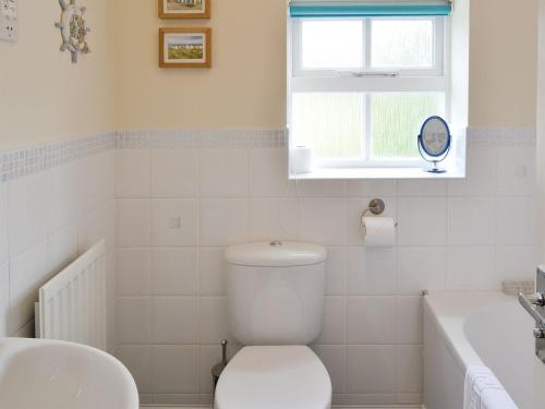 a bathroom with a toilet and a sink and a window at Teal Cottage in Embleton