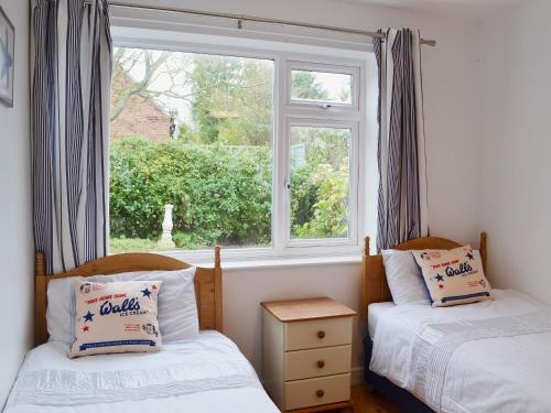 two twin beds in a room with a window at Coastal Hideout in Wells next the Sea