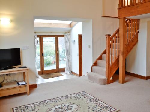 uma sala de estar com uma escada e uma televisão de ecrã plano em Taw em Great Torrington