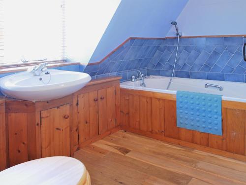 a bathroom with a sink and a bath tub at Burnt House Cottage in Barking