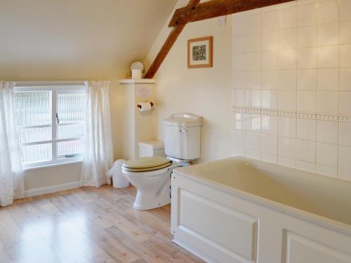 La salle de bains est pourvue de toilettes et d'une baignoire. dans l'établissement Swallows Cottage, à Tipton Saint John
