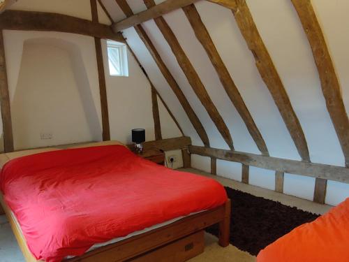 a bedroom with a red bed in an attic at Burnt House Cottage in Barking