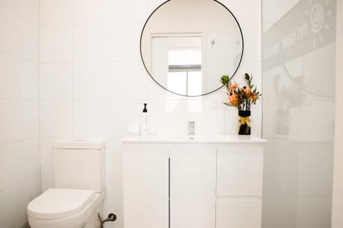 a white bathroom with a sink and a mirror at Beachcomber Holiday Units in Lakes Entrance