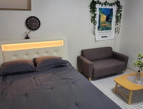 1 dormitorio con 1 cama, 1 silla y 1 reloj en On the main street of HBC en Seúl