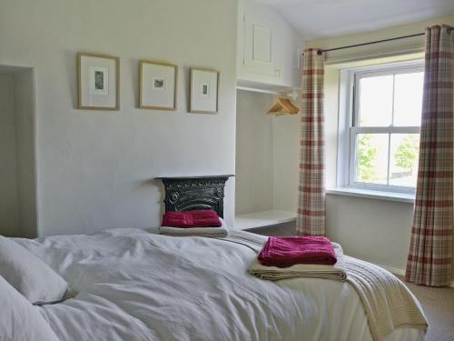 a bedroom with a bed with two pillows and a window at Gardenwell Cottage in Hawes
