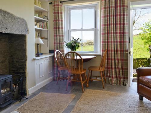 un soggiorno con tavolo, sedie e finestra di Gardenwell Cottage a Hawes