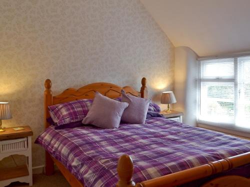 a bedroom with a bed with pillows and a window at Sweet Briar Cottage in Holford