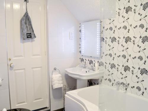 a bathroom with a white tub and a sink at Harwood Dale Cottage in Kendal