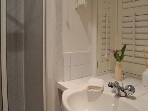 a white bathroom with a sink and a shower at The Studio in Cuckfield