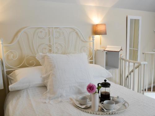 a white bed with a tray with cups and flowers on it at The Studio in Cuckfield