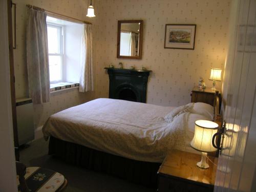 1 dormitorio con 1 cama, chimenea y ventana en 3 Townhead Cottages, en Grasmere