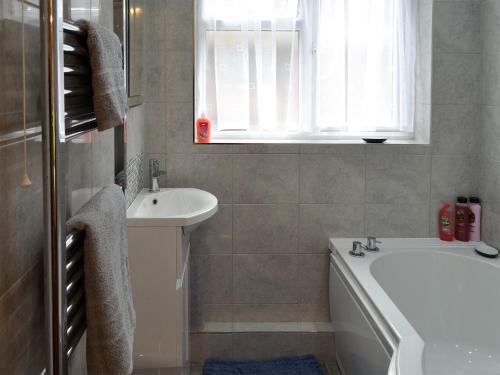 a bathroom with a tub and a sink and a bath tub at Hideaway Cottage in Kingsgate