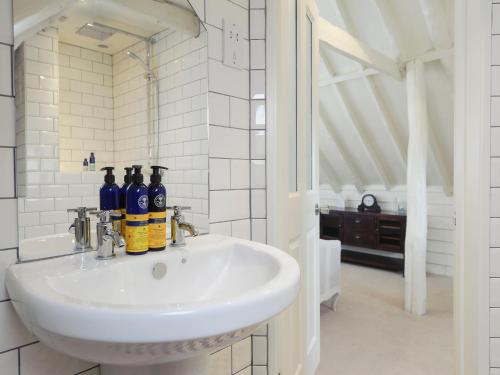 a bathroom with a white sink with bottles on it at The Dairy in Heveningham