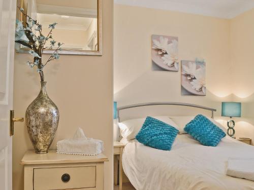 a bedroom with a bed and a vase on a night stand at Tarifa 7 in Bigbury on Sea