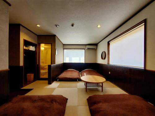 a room with two beds and a table and a window at 久住高原 赤川温泉スパージュ-Spaju in Taketa