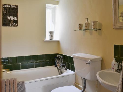 a bathroom with a toilet and a tub and a sink at Reedcutters in Reedham