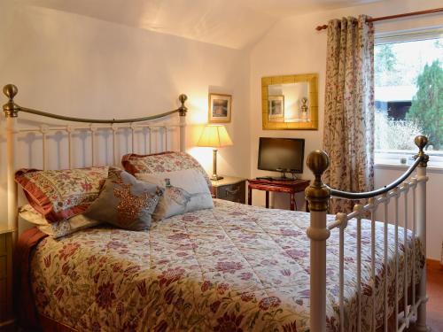 a bedroom with a bed and a tv and a window at Croiscrag Cottage in Aboyne