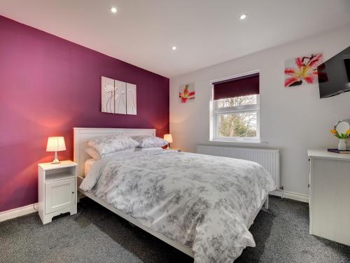 a bedroom with a purple accent wall and a bed at Graces Dairy in Wooler