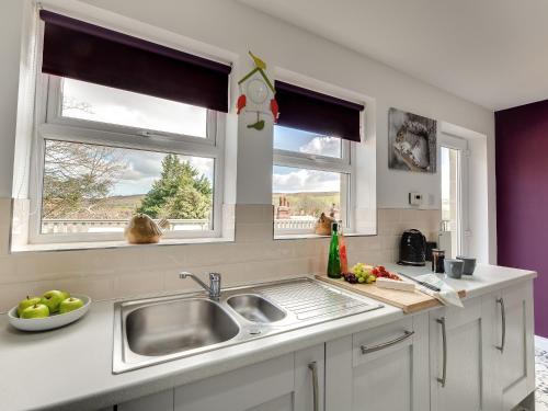 a kitchen with a sink and two windows at Graces Dairy in Wooler
