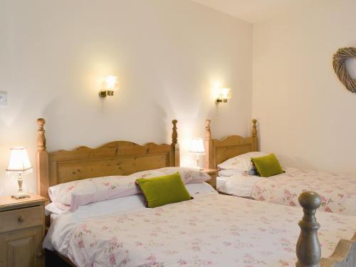 a bedroom with two beds with green pillows at Harriets Hideaway in Braithwaite