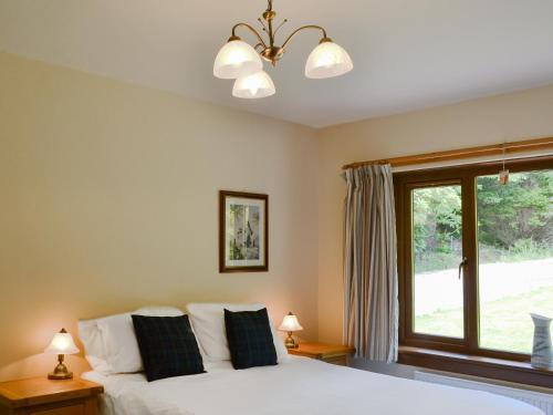 a bedroom with a white bed and a window at Pinewood in Gairlochy