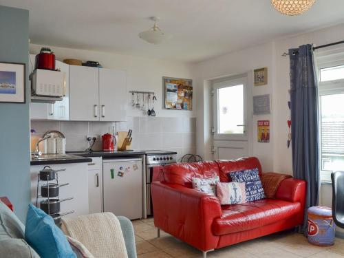 a living room with a red couch and a kitchen at Woolacombe Folly in Mortehoe