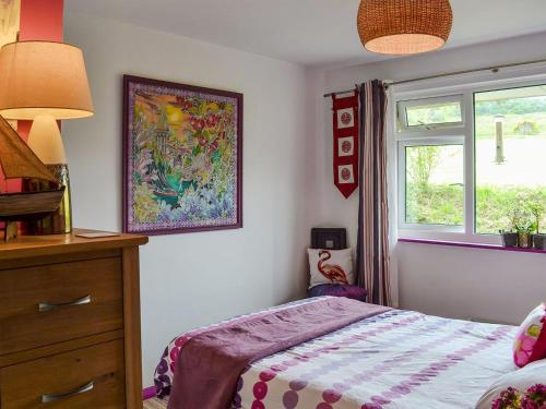 a bedroom with a bed and a dresser and a window at Woolacombe Folly in Mortehoe
