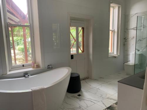 a white bathroom with a tub and a window at Bungala House in Yankalilla