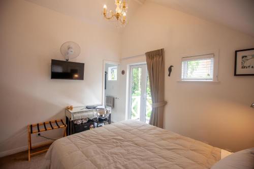 a bedroom with a bed and a desk and a window at Dove Cottage in Auckland