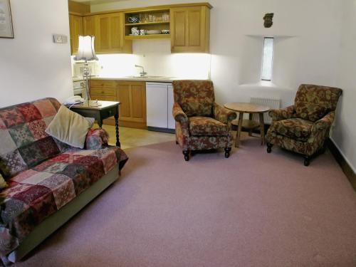 ein Wohnzimmer mit einem Sofa, 2 Stühlen und einem Tisch in der Unterkunft The Coach House in Thirlmere