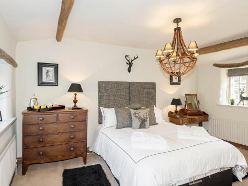 a bedroom with a bed and a dresser and a chandelier at Narrowgates Cottage in Barrowford
