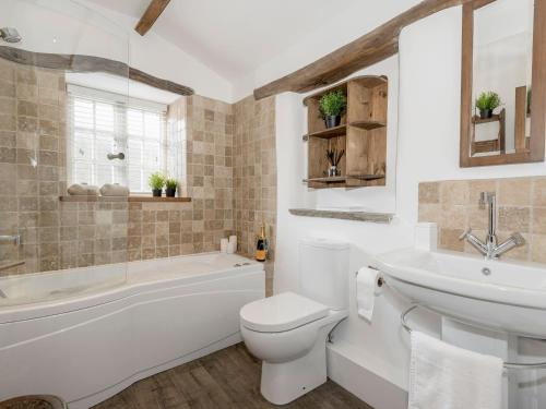 a bathroom with a white toilet and a tub and a sink at Narrowgates Cottage in Barrowford